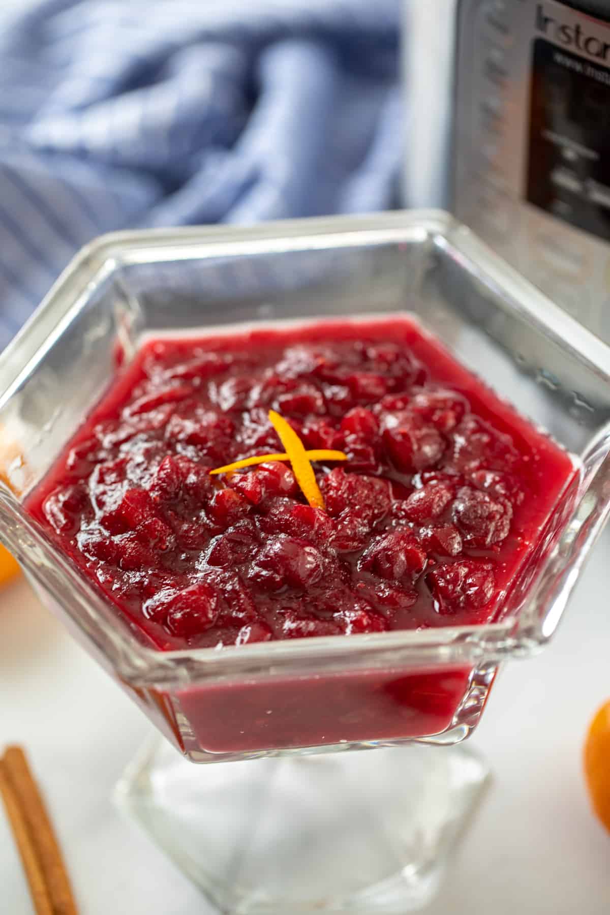 Instant Pot Cranberry Sauce in a clear glass serving dish next to instant pot. 