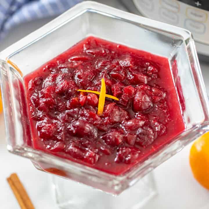 Cranberry sauce topped with orange zest next to the inner pot.