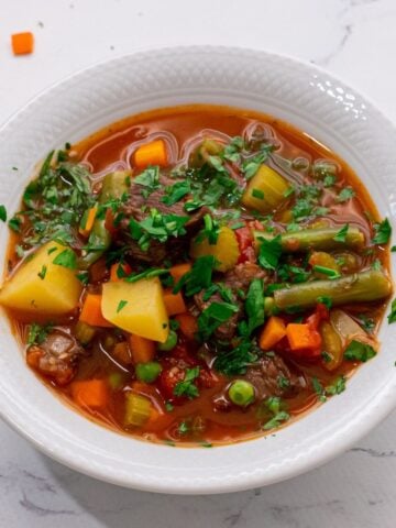Bowl of Vegetable Beef Soup topped with parsley.