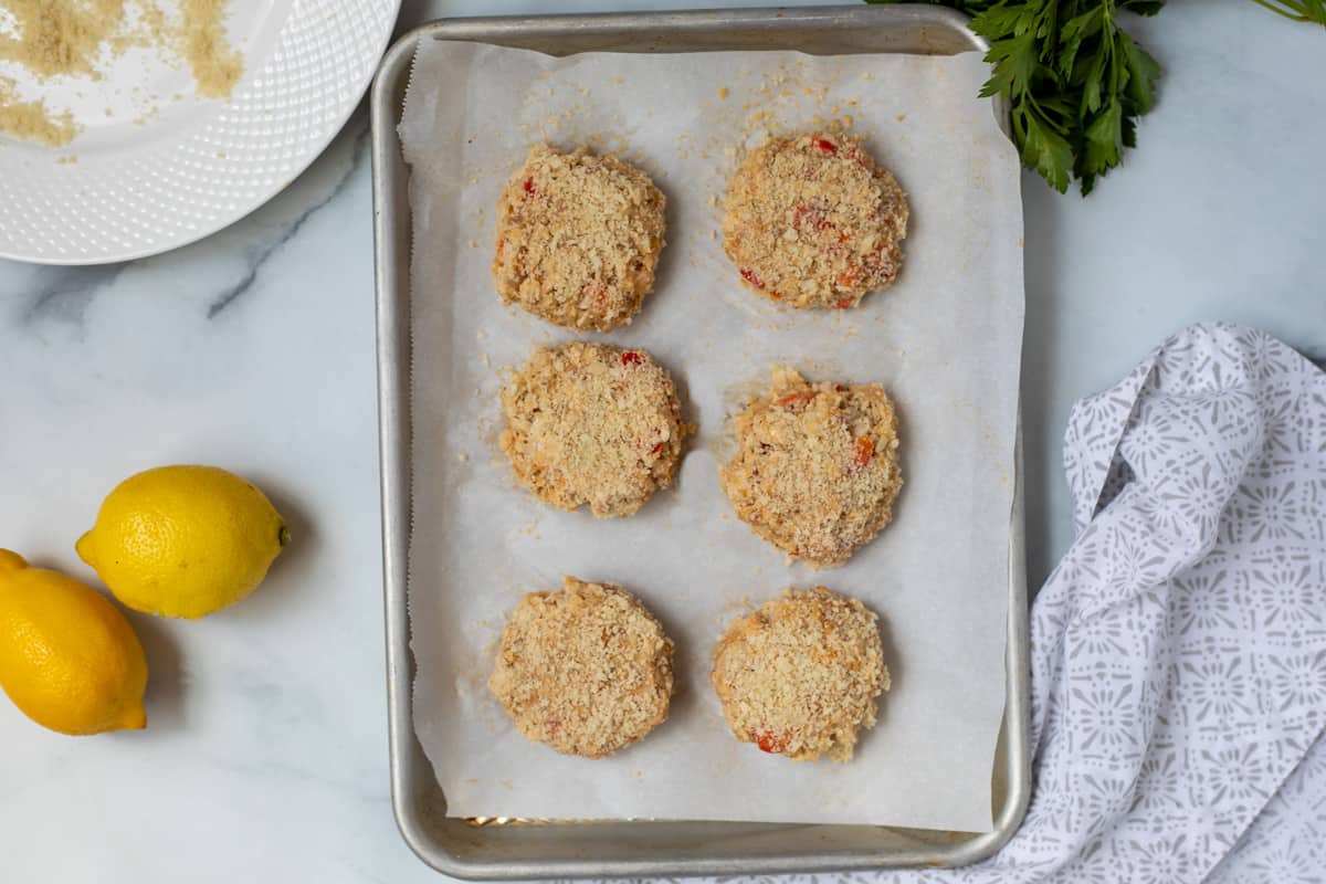 Shaped and breaded Crab Cakes on baking sheet. 
