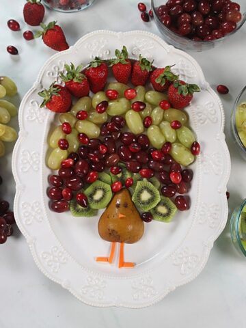 Fruit arranged to look like feathers of a turkey on a white platter.