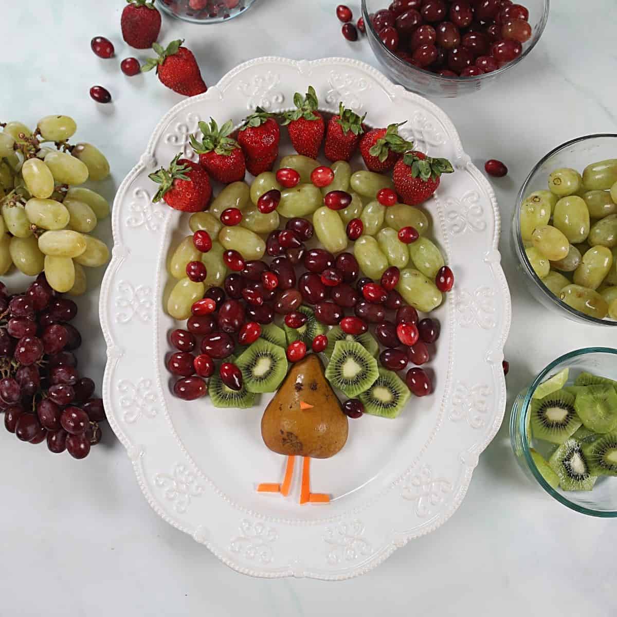 Fruit arranged to look like feathers of a turkey on a white platter.