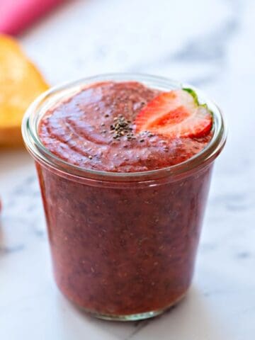 Stawberry Chia jam in glass jar next to toast.
