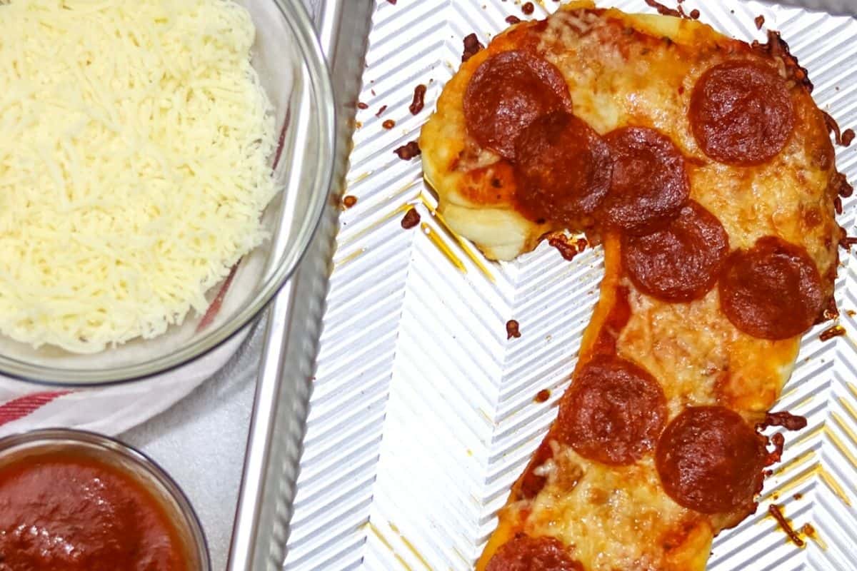 Baked Pepperoni pizza on a sheet pan shaped like a candy cane.