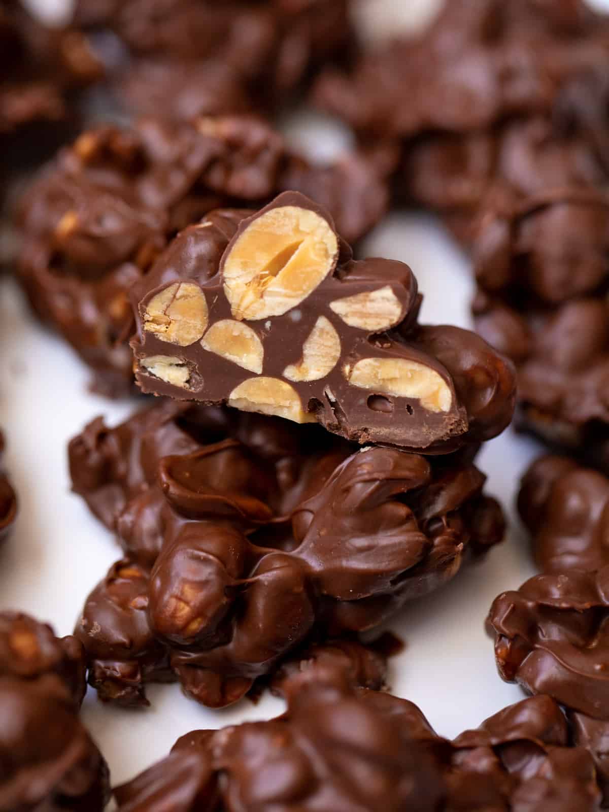 Close up of crockpot candy cut open to show peanuts covered in melted chocolate. 