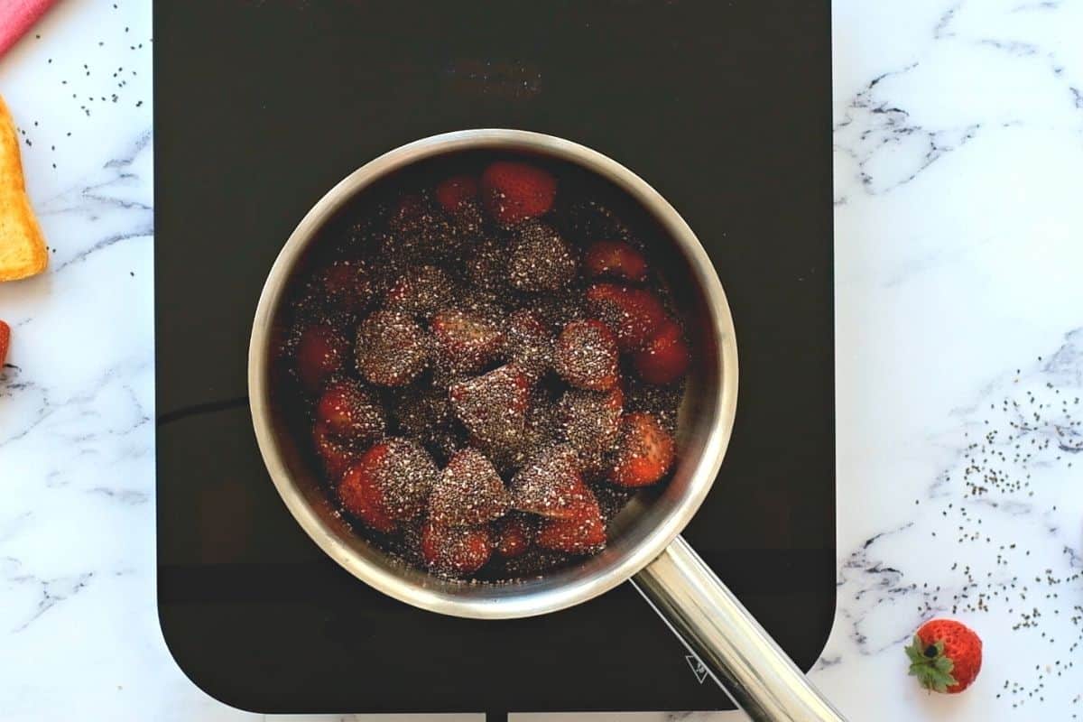 Strawberries in saucepan with chia seeds and maple syrup. 