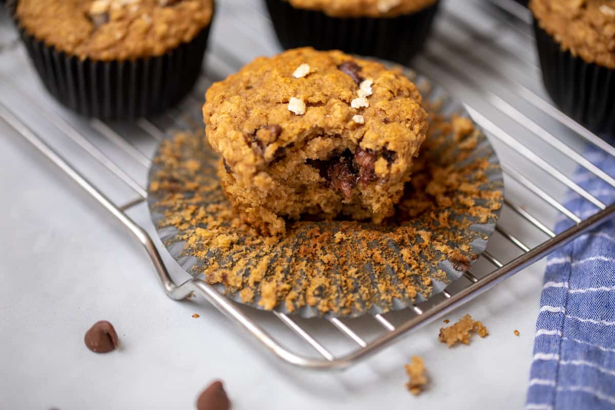 Chocolate Chip muffin on cooling rack showing a bite out of muffin.