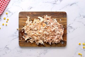 Shredded chicken on cutting board.