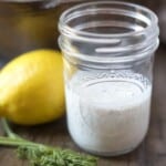 Jar of homemade ranch dressing next to dill and lemon.
