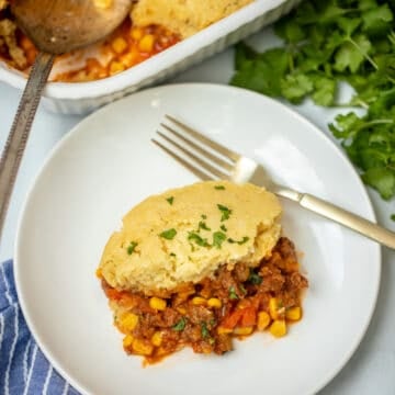 Slice of tamale pie on white plate with casserole dish in the background.