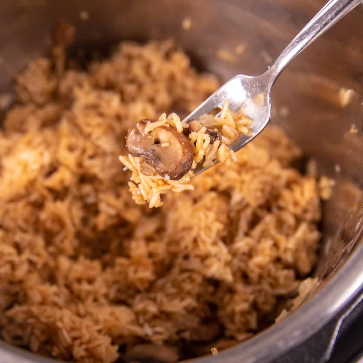 Fork showing rice pilaf being fluffed in inner pot.