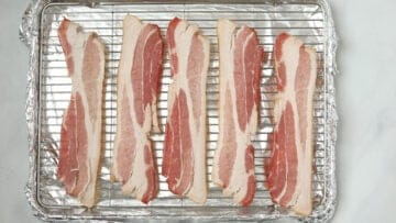 Raw bacon on sheet pan.