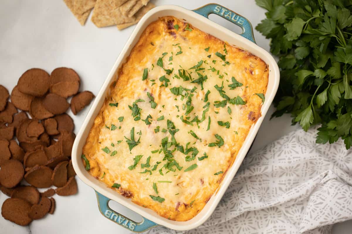 Baked Reuben Dip topped with fresh parsley next to triscuits and rye chips.