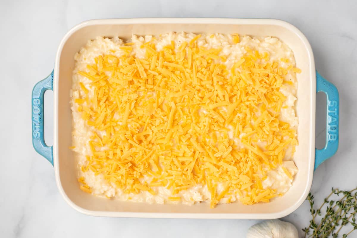Chicken and rice casserole in blue casserole dish topped with shredded cheese.