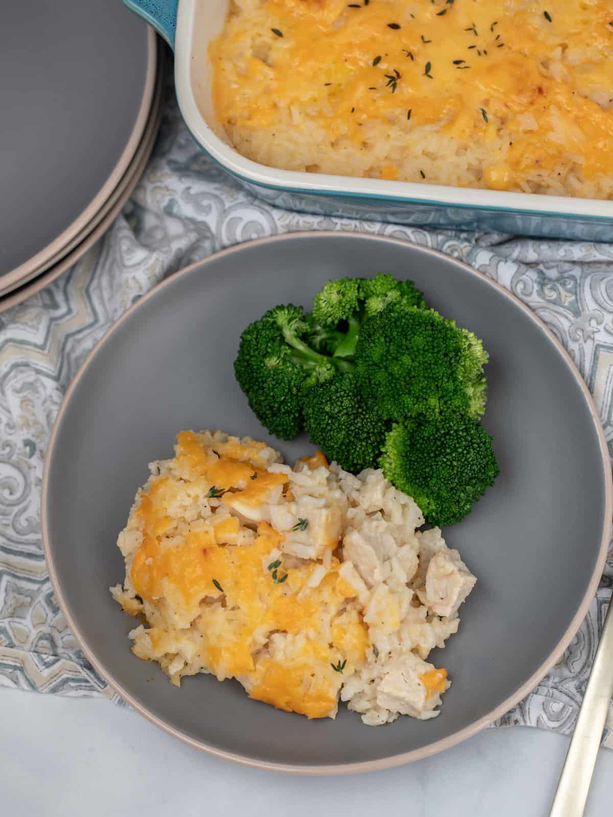 Chicken and Rice Casserole dished out on gray plate with steamed broccoli.