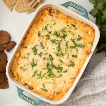 Baked Reuben Dip topped with fresh parsley next to triscuits and rye chips.