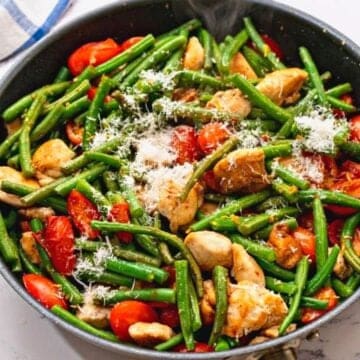 Skillet with chicken, tomatoes, green beans, and tomatoes.