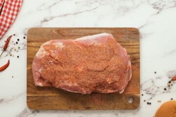 Spice rubbed pork butt on cutting board.