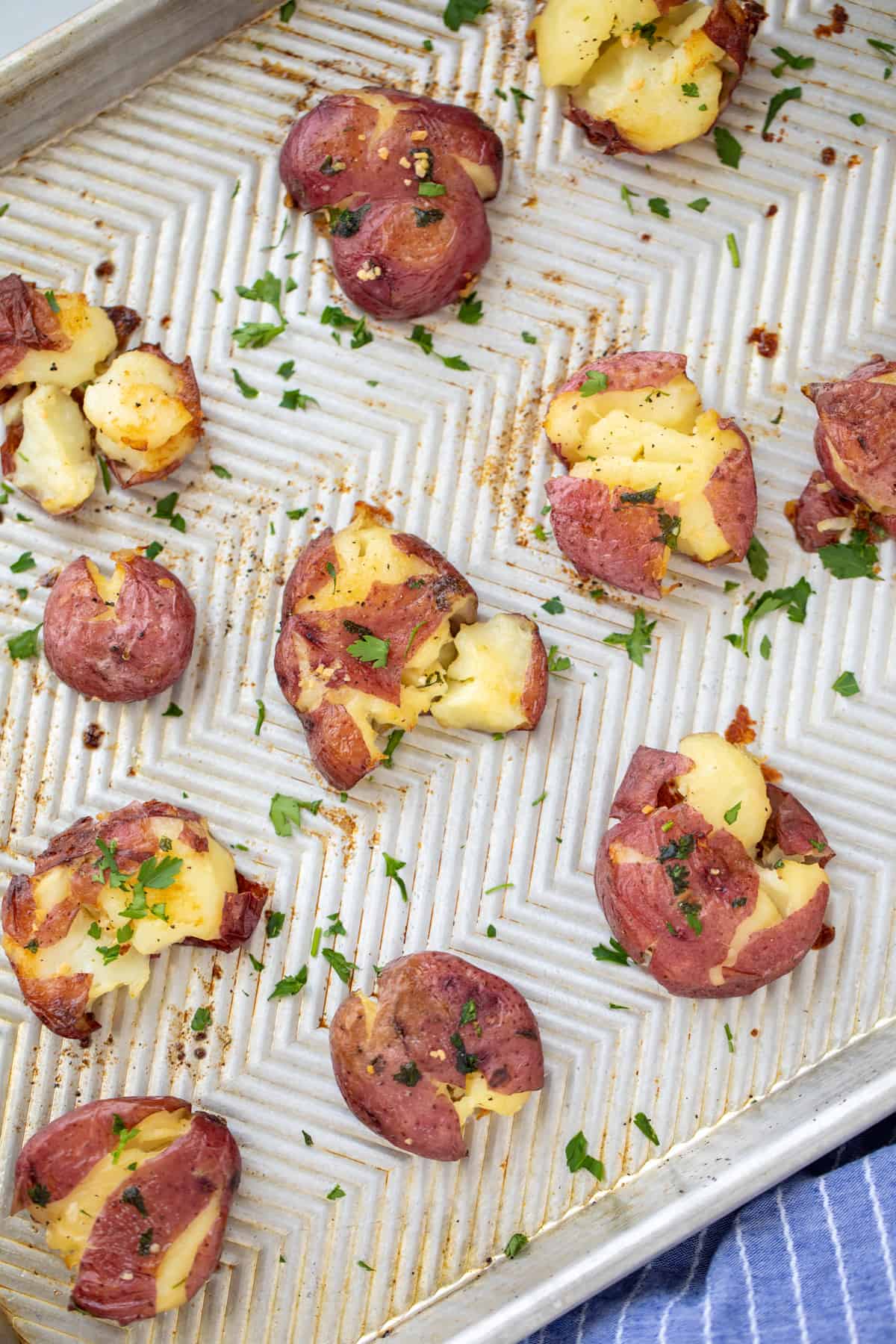 Smashed potatoes on sheet pan with parsley.
