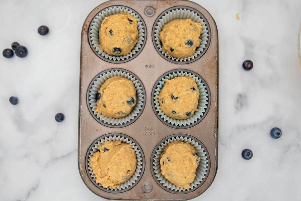 Blueberry muffin batter in muffin tin.