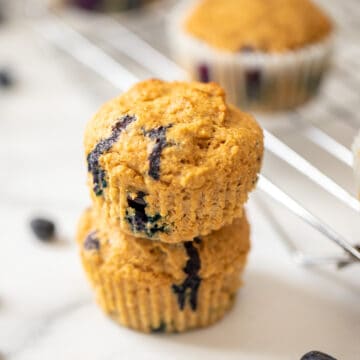 Two whole wheat blueberry muffins stacked on top of each other.