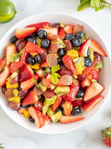 Summer fruit tossed together in serving dish topped with mint.