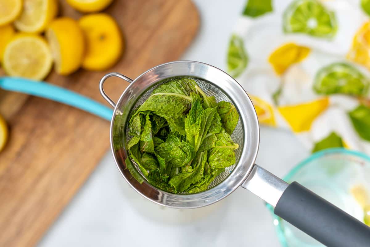 Mint being strained out of fresh mint lemonade.