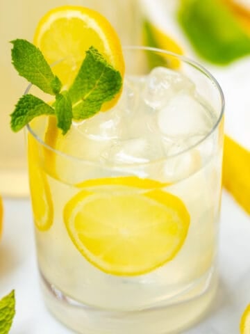 Glass of mint lemonade garnished with sliced lemon and fresh mint.