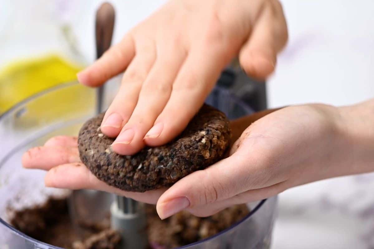 Hands shaping black bean burger into a burger patty.