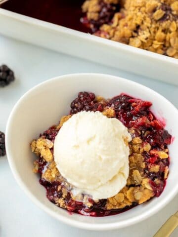 Blackberry Crisp in white bowl topped with ice cream.
