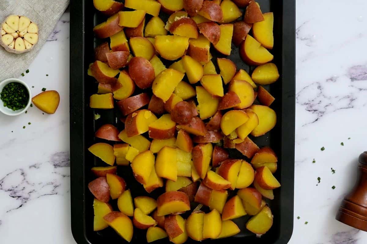 Boiled Red potatoes on baking sheet cooling after cooking.