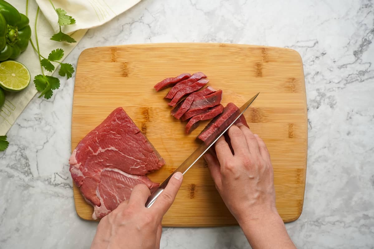 Sirloin Steak thinly sliced on cutting board.