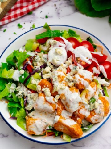 Bufflalo Chicken Salad with creamy ranch and crumbled bleu cheese dressing plated in large bowl.