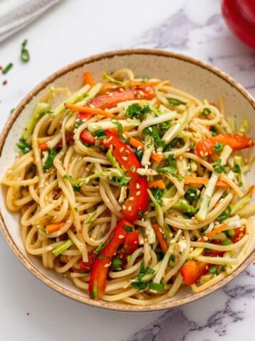 Cold noodle salad in bowl topped with sesame seeds.