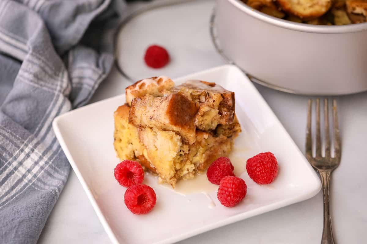 Instant Pot French Toast Casserole on white plate next to Instant Pot garnished with raspberries.