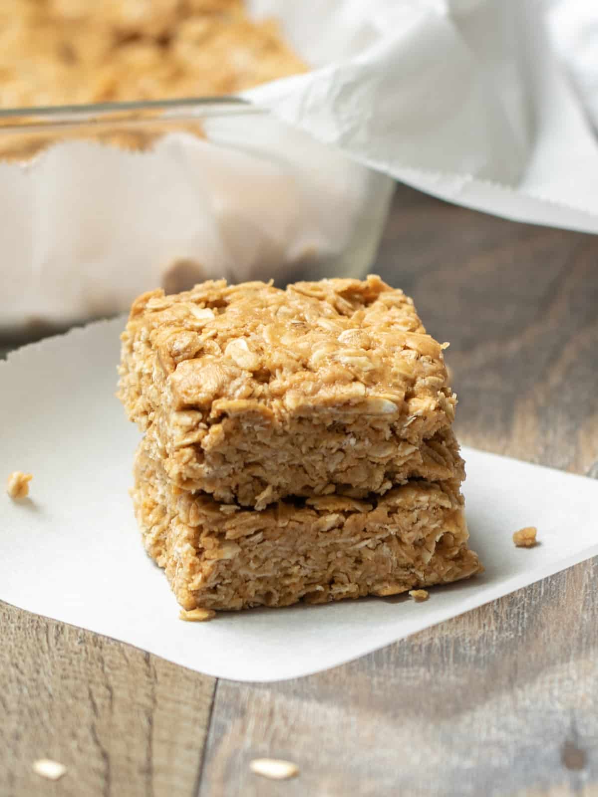 PB Oat Bars stacked ont top of eachother next to tray of peanut butter oatmeal bars.