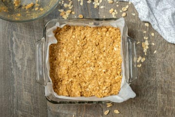 PB oatmeal bars in baking pan lined with parchment paper.