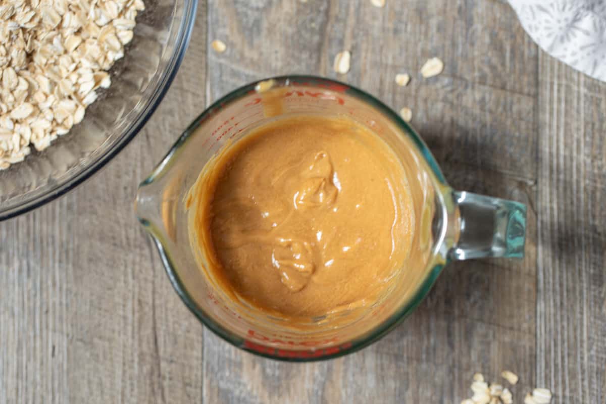 Glass measuring cup with heated peanut butter and honey mixed together.