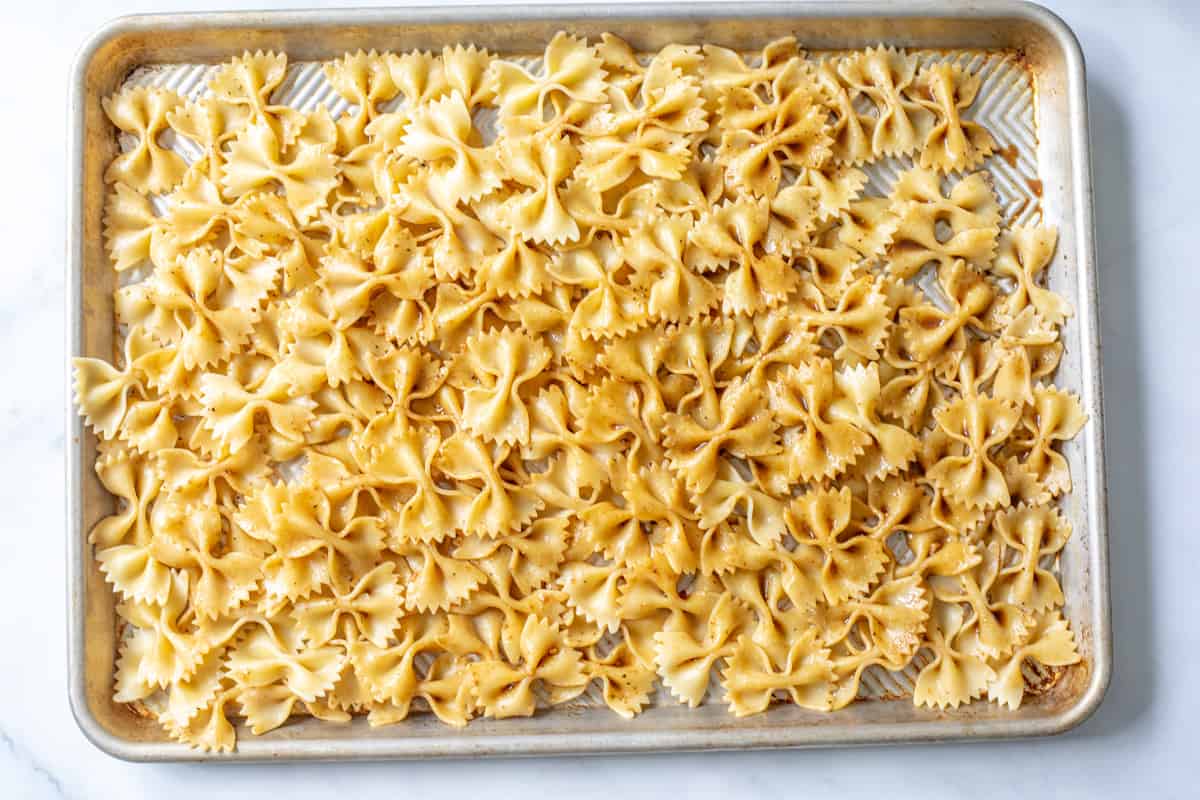 Dressed pasta spread out on a sheet pan.