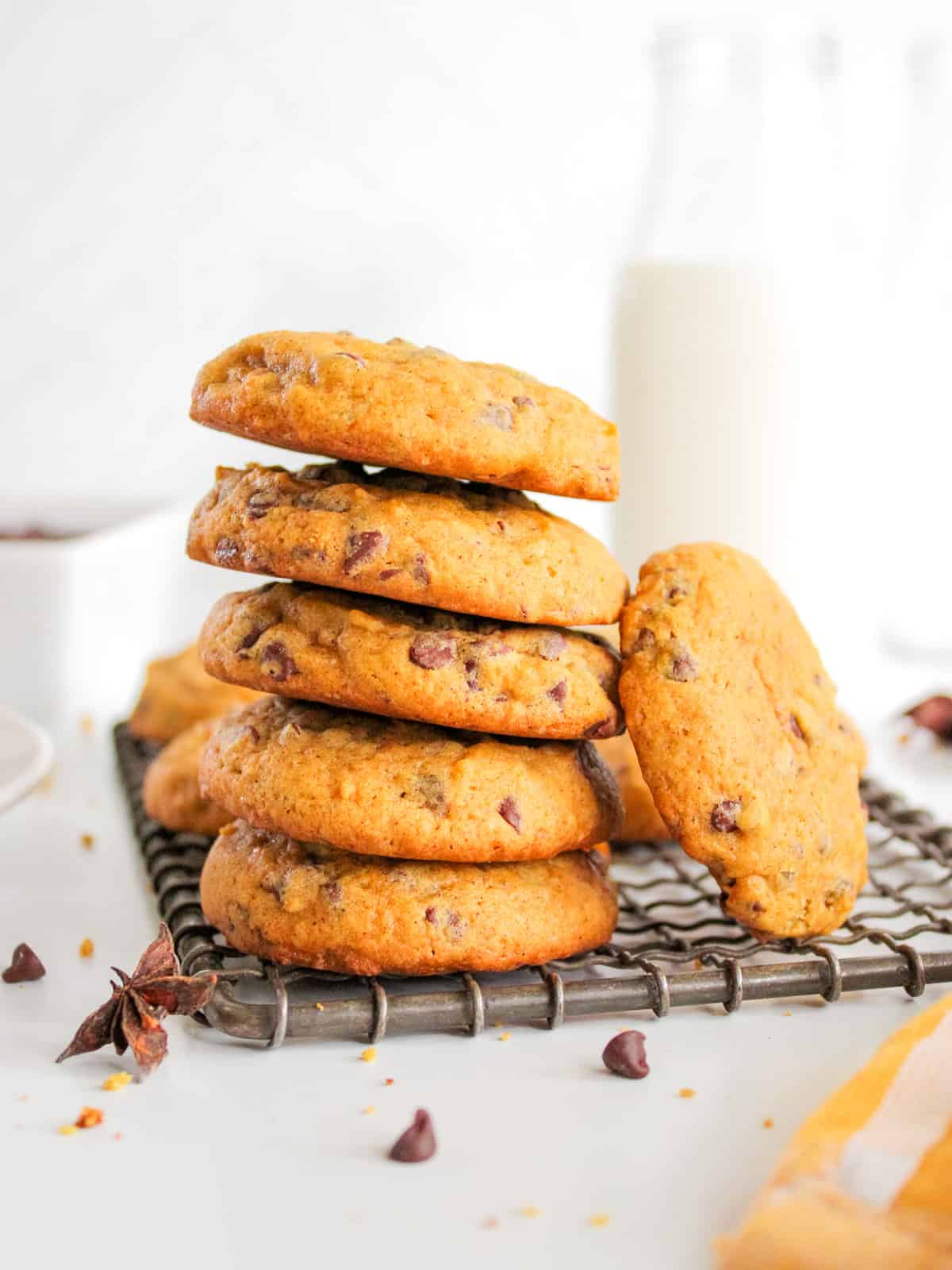 Stack of baked pumpkin chocolate chip cookies on cooking rack.