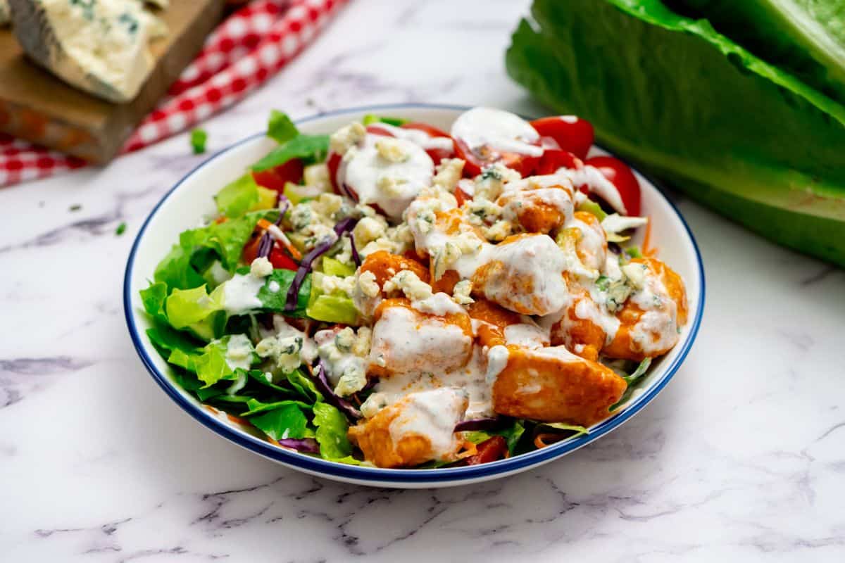 Bufflalo Chicken Salad with creamy ranch and crumbled bleu cheese dressing plated in large bowl.