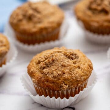 Close up of gluten-free cinnamon streusel muffin in white baking cup.