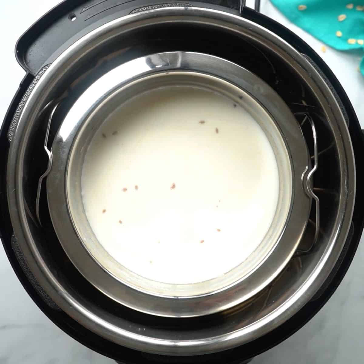 Stainless steel bowl with milk and oats inside inner pot of instant pot.