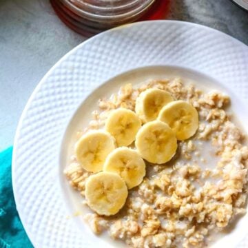 Bowl of Instant Pot Oatmeal topped with sliced banana and maple syrup.