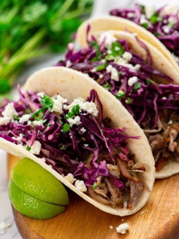 Tortilla filled with slow cooker carnitas and topped with Mexican slaw and queso freso.