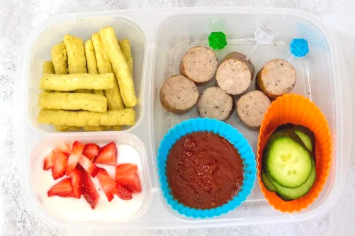 Sausage skewers with side of marinara, cucumbers, yogurt, and pea crisps in lunch container.