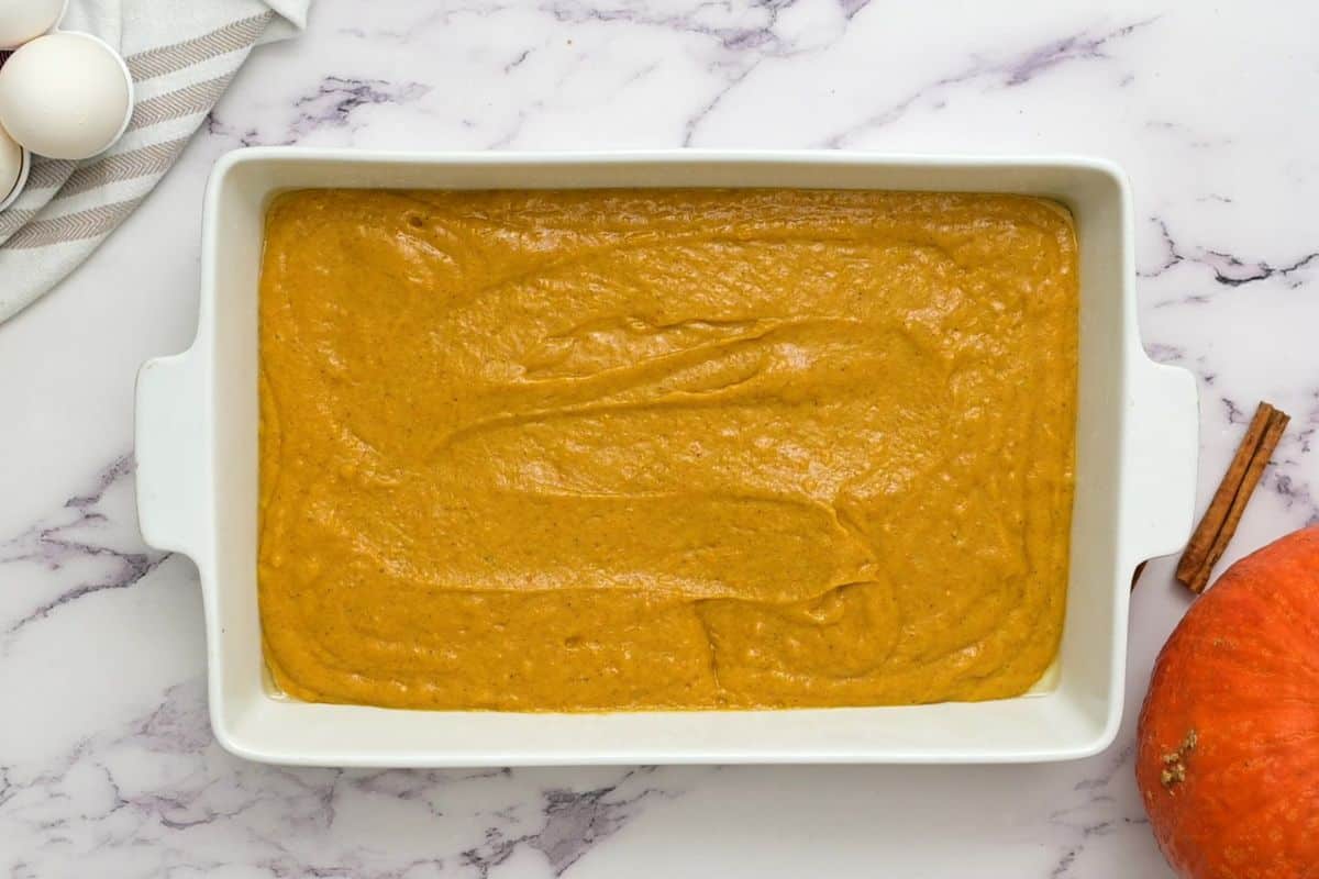 Pumpkin cake batter spread out in a 9x13 white baking dish.