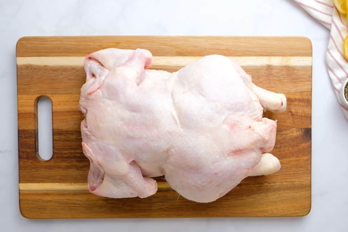 Raw chicken sitting on cutting board.