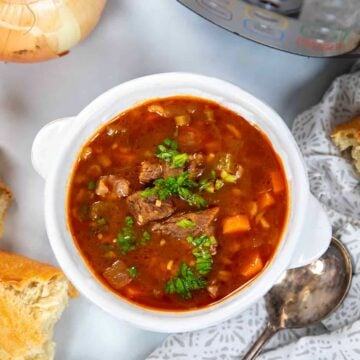 Bowl of Beef and Barley Soup next to crusty bread.
