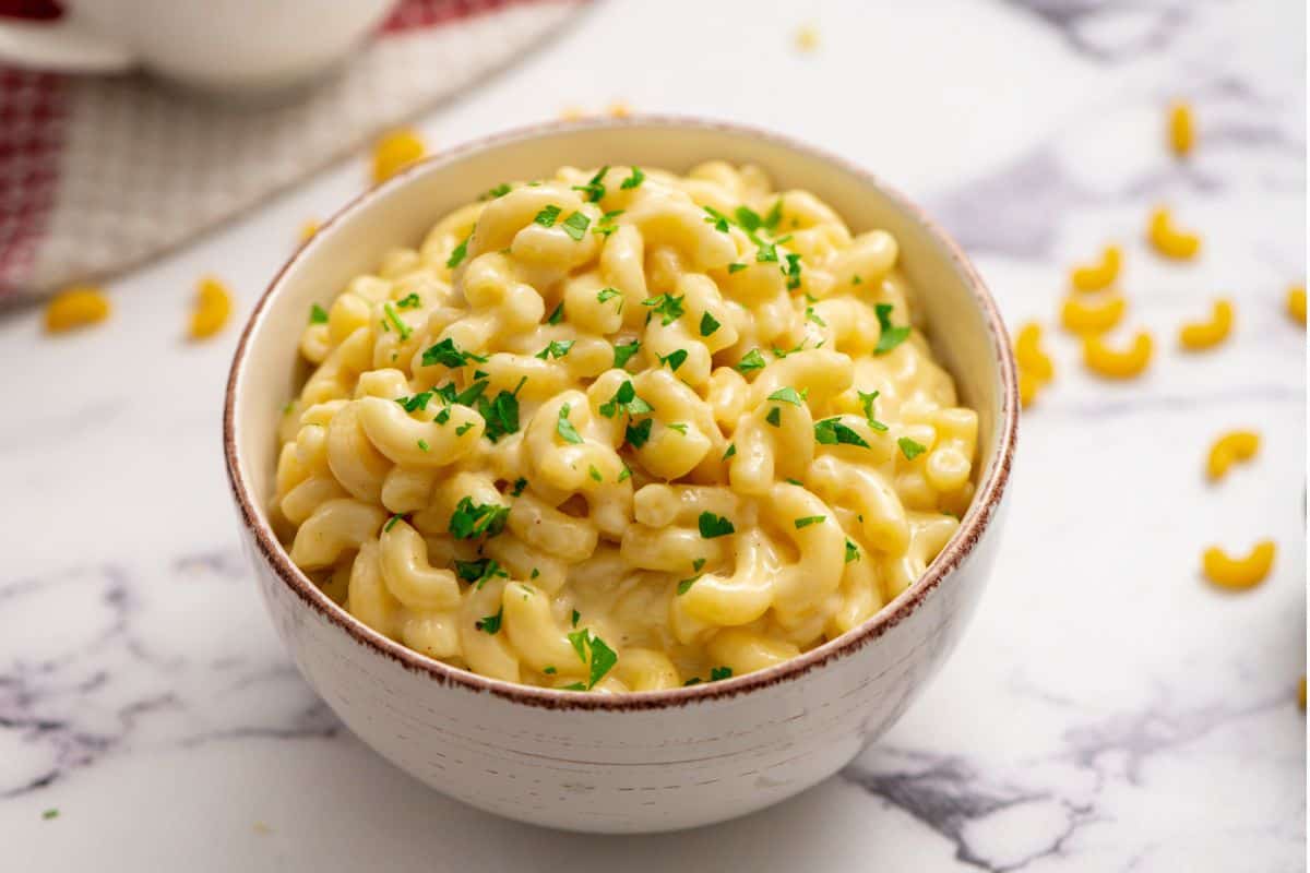 Bowl of white cheddar mac and cheese topped with chopped parsley.